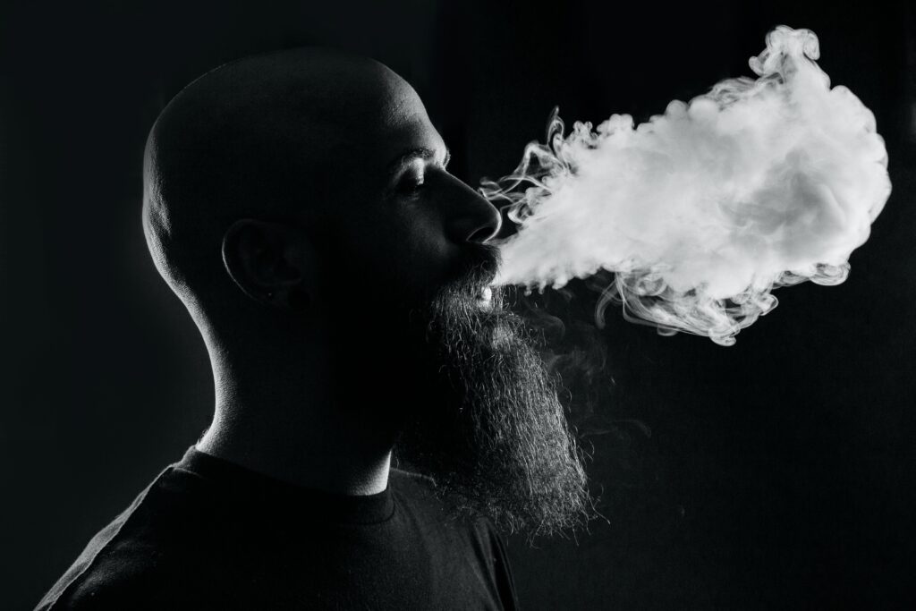 person blowing smoke in front of black background