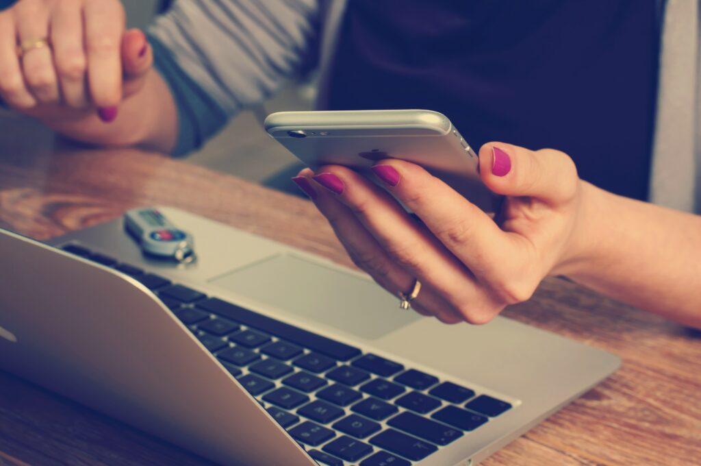 person on iphone while on laptop