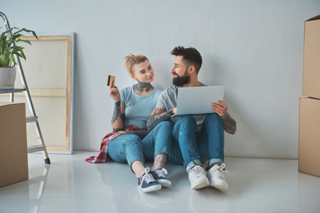 smiling couple with laptop and credit card shopping