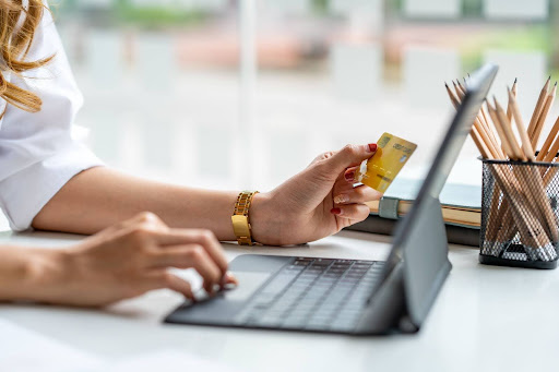 women hold a credit card in front of her computer