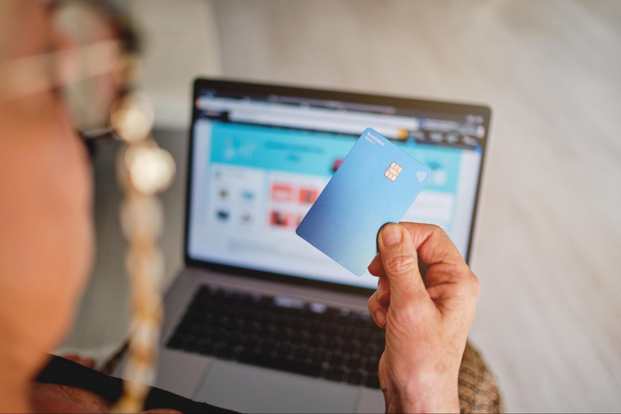 a hand holding a Visa credit card showing the Visa Acquirer Monitoring Program